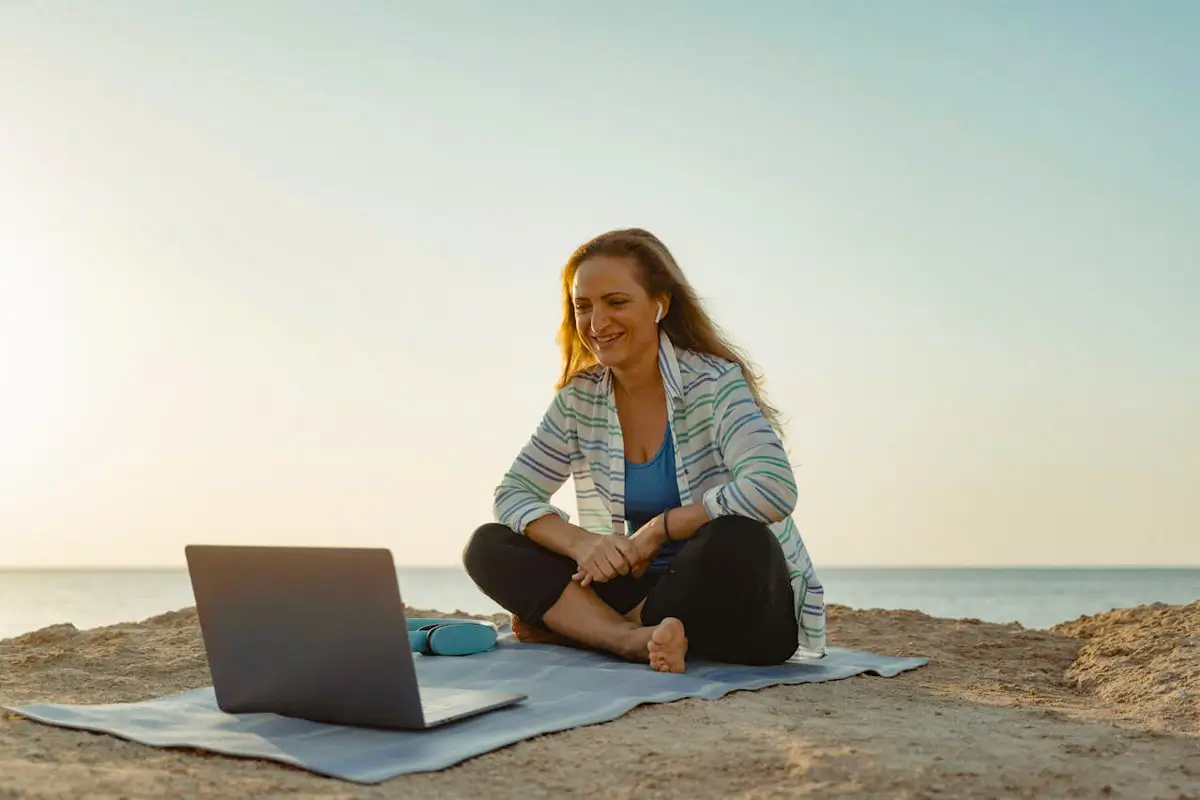 Digitale Nomadin arbeitet mit Laptop am Strand – eine eigene Website gibt Freiheit und Unabhängigkeit